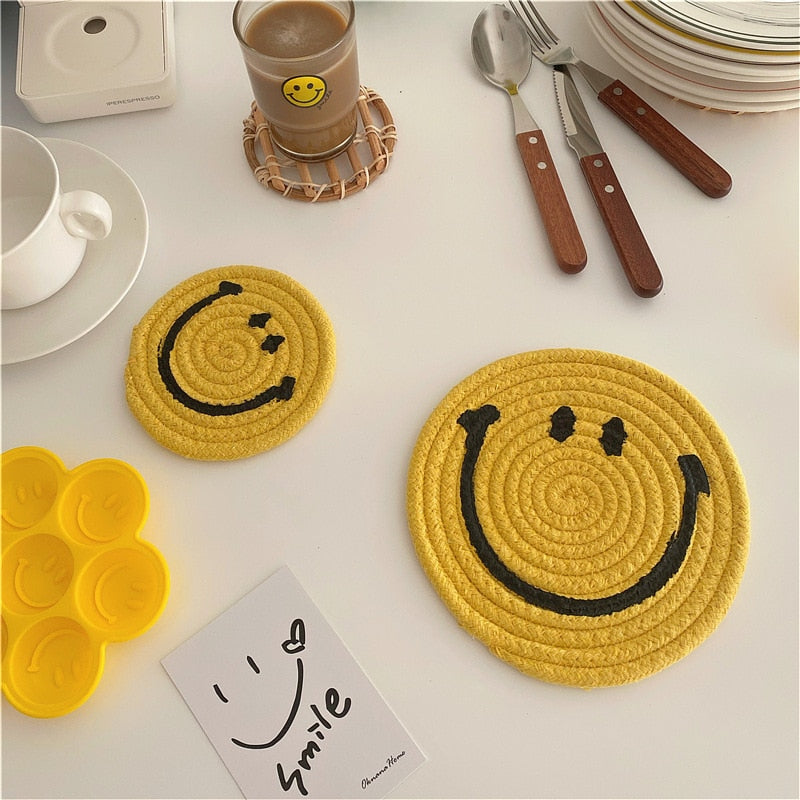 Yellow smiley coasters beside a cup and plates